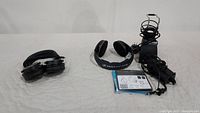 Two pairs of headphones — Sennheiser wireless on-ear headphones with charging station, manual, and power adapter on the right; folded Presonus monitoring headphones on the left
