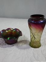 Photo of an amethyst Carnival Glass fluted bowl with an iridescent finish and a Pepita Jugendstil vase showing color gradient and swirling pattern