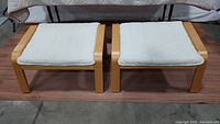 Two IKEA POANG ottomans side by side showing overall condition and design with light wood frames and light cushions.