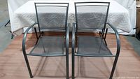 Two metallic gray steel mesh patio chairs side by side showing full front view.