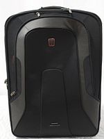 Front of black TECH branded softside luggage showing zippered compartment and logo badge
