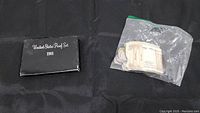Black outer box labeled 'United States Proof Set 1981' with a sealed plastic bag containing various coins and folded banknotes