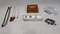 Full overview of jewelry pieces, wooden jewelry box, and bag of coins arranged on a white background
