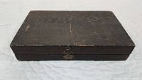 Closed dark wooden box with visible wood grain and minor wear.