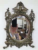 Front view of ornate brass beveled glass mirror reflecting room.