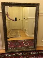 Full view of large antique wall mirror showing reflective surface and frame.
