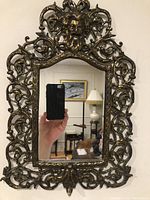 Full view of gilt bronze beveled mirror with openwork scroll frame and Bacchus bust