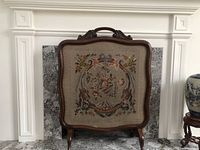 Front view of Edwardian walnut fireplace screen showing floral needlepoint fabric panel within carved wooden frame.
