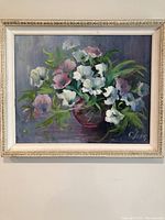 Full view of painted floral still life showing flowers in a red vase with off-white ornate frame.