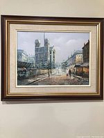 Framed oil painting showing Paris street view with cathedral and pedestrians.
