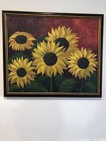 Full view of oil painting depicting five sunflowers with deep red background in a framed wood and gold border frame.