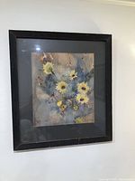 Framed watercolor painting of yellow sunflowers on blue and grey background, viewed straight on.