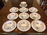 Overview of nine place settings, each with soup bowl, saucer and dinner plate, plus additional stacked side plates in back