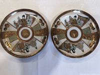 Pair of Japanese Kutani porcelain plates showing hand-painted traditional figures and gold detail work on the front sides