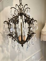 Close-up of chandelier body showing ornate brass scrolling and crystal prisms