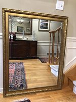 Front view of rectangular gilt mirror reflecting interior