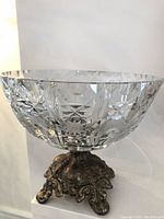 Side view showing heavy cut crystal bowl mounted on detailed brass pedestal base with ornate design.