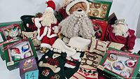 Full assortment of vintage Christmas decor and ornaments including Santa figures, boxed ornaments, stockings, and pillows arranged for display.