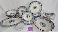 Full set of ceramic dinnerware displaying plates, bowls, serving platters, and gravy boat with snowman motif on a blue border background.