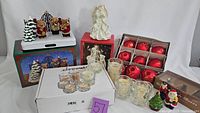 Full view of Christmas ornaments, figurines, and candles set showing boxed red ball ornaments, angel figurines, Santa figurine, tea lights, and candle holders.