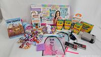 Overview of all included items in the bundle showing crayons, Littlest Pet Shop figures, Make It Real kit, Cat Crimes board game, Terrarium kit, and NES console with controllers