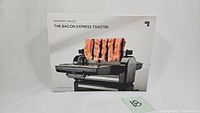 Front view of boxed Sharper Image Bacon Express Toaster showing cooked bacon strips on the appliance illustration.