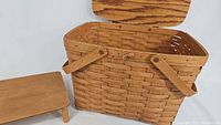 Photo showing the vintage Longaberger basket with hinged lid open and the wooden serving table placed next to it on white background.