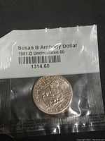 Susan B Anthony Dollar 1981-D Uncirculated coin in original plastic packaging, showing reverse side with eagle landing on the moon holding an olive branch, and label indicating uncirculated status.