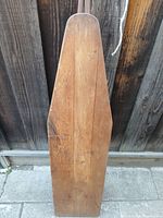 Top view of the rectangular wooden ironing board top with rounded edges, showing wood grain and age marks.
