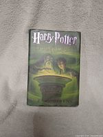Front cover of the hardcover book showing main illustration of Dumbledore and Harry Potter with magical basin.