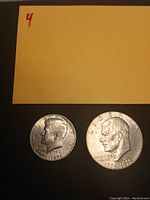 Close-up photo of the obverse side of two Bicentennial coins dated 1776-1976 including Kennedy and Eisenhower with visible profile heads and mint details.