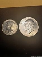 Obverse side of two coins: 1976 Bicentennial Kennedy Half Dollar and Eisenhower Bicentennial Dollar; both show profile portraits in circulated condition.