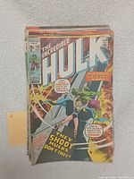 Photo showing The Incredible Hulk #142 comic on top of a small stack of comics, highlighting worn condition with visible creases and edge wear