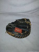 Top side view of the black Rawlings catchers mitt showing the red Rawlings label and tan lacing details.