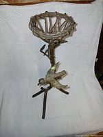 Front view of vintage twisted iron candle stand with basket-style candle holder and bird design