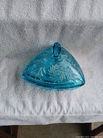 Top-down view of the triangular blue covered dish showing floral pattern and lid handle.