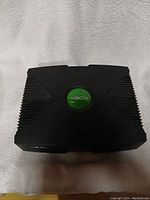 Top view of the original Xbox console showing the large 'X' and green Xbox logo in the center.