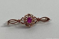Front view of the gold brooch showing central ruby and diamond cluster