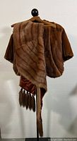 Photo showing both brown mink fur stoles/shawls displayed on a mannequin, one shorter cape style and one longer with tassel fringe