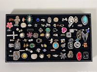 Overhead view of entire tray showing more than 60 assorted rings.