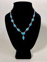 Necklace displayed on black bust showing full length and V-shaped pendant design