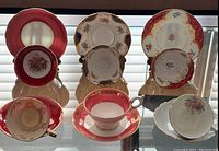 Four bone china teacups and saucers arranged showing various floral patterns and red/gold color schemes