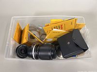 Plastic bin with two lenses, multiple yellow Kodak filter envelopes, black pouch