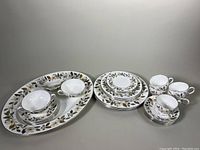 Full view of the entire bone china dinnerware set for 4 showing platter, stacked plates, bowls, teacups, and saucers arranged.