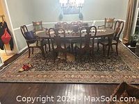 Wooden dining table with six chairs on a patterned rug; visible scratches on table surface and some wear on chairs