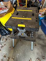 Side view showing black plastic surface, foldable legs, and yellow measurement guides.