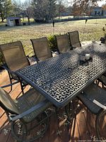 Angled view of rectangular lattice-top table with five chairs on one side