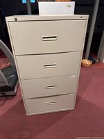 Front view of first large beige metal filing cabinet with 4 drawers and locking mechanism on the top drawer.