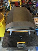 Top view of black Ooni pizza oven body with embossed Ooni logo on lid and retracted legs