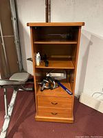 Front view of a medium brown wooden storage shelf showing three shelves and two drawers with metal handles.